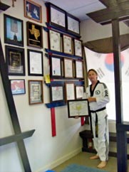 Master Gary White Poses with his wall of awards